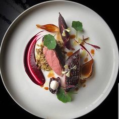 a white plate topped with food and garnish on top of a black table