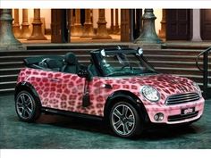 a pink and black mini car parked in front of a building with steps leading up to it