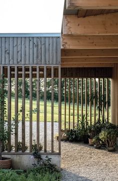 an open air building with wooden slats on the sides and plants in pots outside