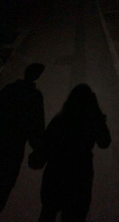 the shadow of two people standing in the dark