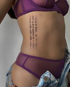 a woman with a tattoo on her stomach wearing a purple bra and blue jean shorts