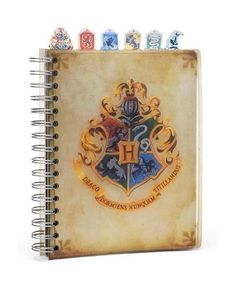 a harry potter notebook with the hogwarts crest on it, surrounded by letters and symbols