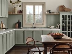 a kitchen filled with lots of green cabinets and counter top next to a wooden table