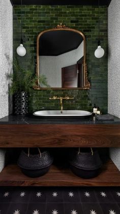 a bathroom with green brick walls and black tile flooring, an oval mirror above the sink