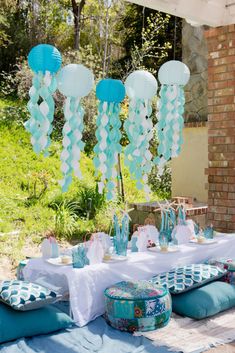 a table with blue and white balloons hanging from it