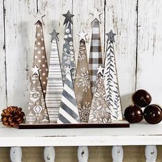 an assortment of wooden christmas trees sitting on top of a white shelf next to apples