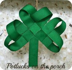 a green ribbon hanging from a hook on a marble wall with a knot in the shape of a four - leaf clover