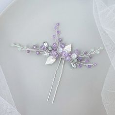 a close up of a hair pin with flowers and leaves on it's side