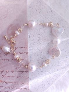 a bracelet with pearls on it sitting on top of a piece of paper