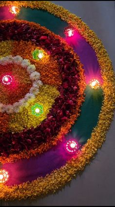 an arrangement of flowers and lit candles in the center of a circular design on a table