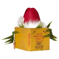 a red and white hat sitting on top of a yellow book with feathers in it