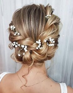 the back of a woman's head with flowers in her hair, wearing a white dress