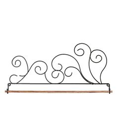 a wrought iron shelf with scroll designs on the top and bottom, against a white background