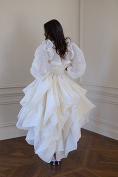 This luxury topper, crafted from crisp silk organdy reminiscent of 1930s haute couture, fastens effortlessly at your waist, transforming any bridal dress into an extravagant gown. Adorned with delicate ruffles that shimmer with each step, it cascades into a sweeping train, the organdy's airy yet structured nature allowing it to float gracefully behind you. Glide down the aisle in full bridal splendour, then detach the tournure to dance freely under the crystal chandeliers. Organdy open-front ski Rooftop Reception, Picturesque Garden, Open Front Skirt, Silk Dressing Gown, Corset Skirt, Puff Dress, Crystal Chandeliers, Knitted Coat, Bridal Shop