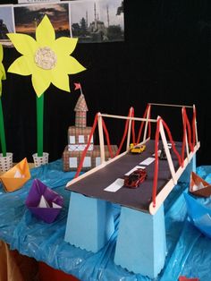 a table topped with paper boats and construction vehicles on top of a blue tarp