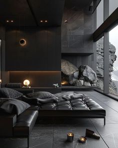 a large black couch sitting in front of a window next to a stone wall and floor