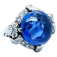 This outstanding antique ring is the embodiment of early 20th century glamour and sophistication. Center of the composition is a gorgeous, untreated, cabochon sapphire of approximate 15.20 carats. It is framed by refined platinum setting and 26 old-cut diamonds of approximately 0.80 carats, H/I colour and vs-si clarity. The ring is beautiful at first glance, but real magic lies in its depths - an entire galaxy seems to be contained within this beautifully mysterious piece. Maker’s Mark: HM Dimensions approx.: 20.00 mm x 20.00 mm / 0.78 in x 0.78 in Size: EU 53 / US 6.5 Weight: 10.64 gr. Sapphire: approx. 15.20 carats Cut: Round Diamonds: 26 diamonds, approx. 0.80 carats total Diamond colour/clarity: H-I / vs-si Cut: Old Real Magic, Maker’s Mark, Antique Ring, Shiny Things, Antique Rings, Cocktail Rings, Early 20th Century, Colored Diamonds, Amazing Women