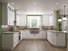 a large kitchen with white cabinets and green accenting the walls, along with hardwood flooring