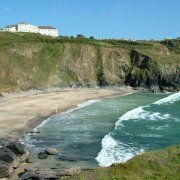 a beach with waves coming in to shore and houses on the cliff side next to it