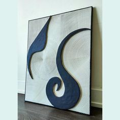 a blue and white abstract painting on the wall next to a wood flooring board