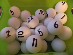 a green bin filled with lots of white balls and numbers on it's sides