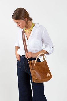 Your bag is proudly made in Lynchburg, Virginia using the finest materials in the world. 10" H x 13" W x 3.5" D 4.5 ” handle drop Crafted with Camel leather* - a full grain pebbled leatherRemovable/adjustable 1/2" crossbody strap that extends from 36" to 48" Straps are bench made with natural Vachetta** leather and solid brass hardware Exterior font pocket Interior hanging pocket and key clip Lined with the acclaimed Liberty of London™ Millie floral fabric Solid Brass Hardware Removable horse ha Rooster Logo, Horse Hair Tassels, Lynchburg Virginia, Brown Leather Totes, Key Clip, Dark Denim Jeans, Leather Cleaning, Small Tote, Horse Hair