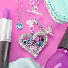 the contents of a purse, lipstick, and necklaces on a pink table top