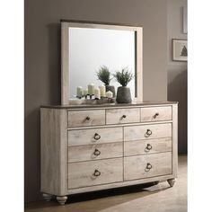 a white dresser sitting next to a mirror on top of a wooden floor covered in candles