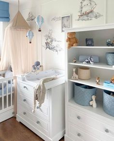 a baby's room with white furniture and blue accessories on the shelves, including a crib