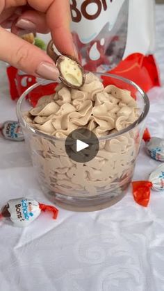 a person scooping some kind of food into a glass bowl with candy on the side