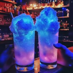 two glasses filled with blue liquid on top of a table