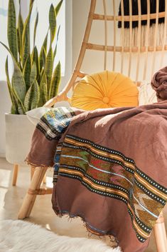 a brown blanket sitting on top of a wooden chair next to a potted plant