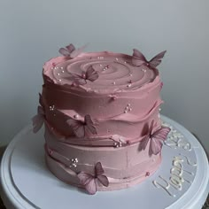 a three layer pink cake with butterflies on it