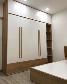 an empty bedroom with white and wood furniture