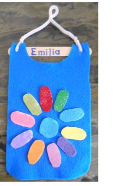 a blue felt bag with colorful flowers on it and a name tag hanging from the front