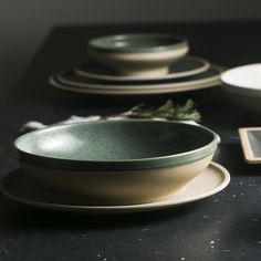 a table topped with plates and bowls on top of a black counter next to a remote control