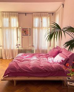 a bedroom with pink bedding and wooden floors