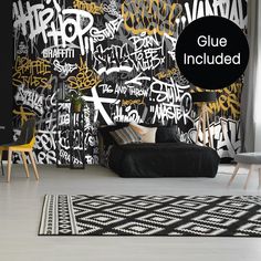 a black and white room with graffiti on the wall, rugs and tables in front of it