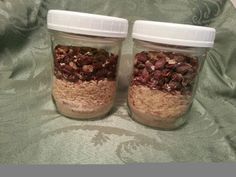 two jars filled with granola sitting on top of a bed