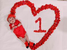 a baby is laying in front of a heart made out of flowers and the number one