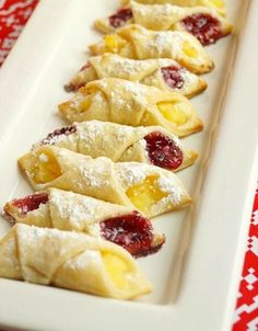 small pastries are lined up on a long white plate with red and white tablecloth