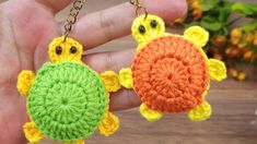 two crocheted turtle keychains are being held by someone's hand