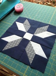 the block is made up of squares with white and black designs on them, along with a sewing needle