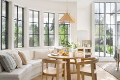 a living room filled with furniture and windows next to a dining table in front of a large window