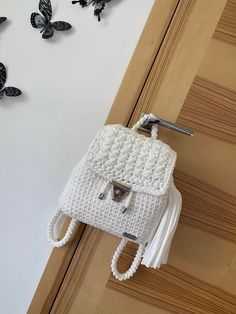 a white crocheted purse hanging from the side of a door next to butterflies