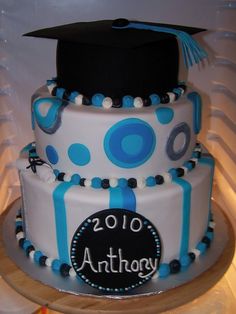 a graduation cake decorated with blue and white stripes, polka dots and a black cap on top