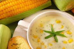 corn on the cob and soup in a white bowl