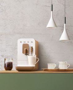 a coffee maker sitting on top of a counter next to some cups and saucers