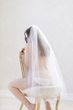 a naked woman sitting in a chair with a veil on her head