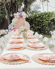 the table is set with pink napkins and place settings for an outdoor dinner party